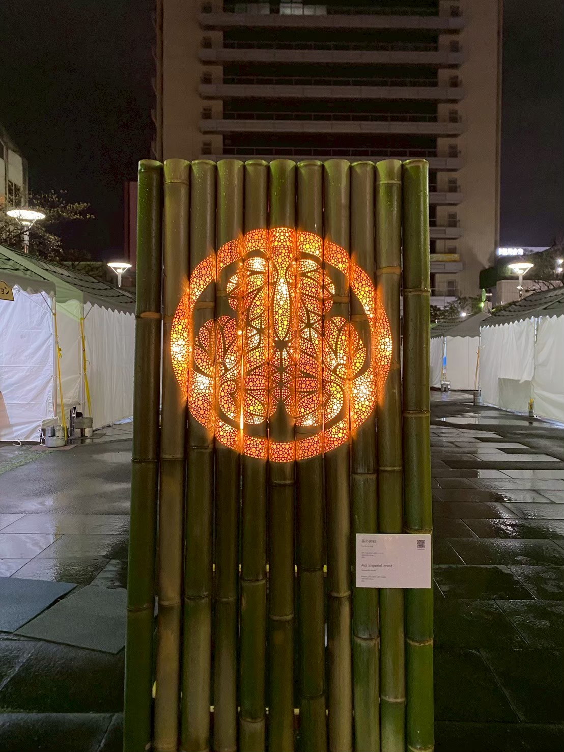 竹を並べた壁面に大きな円形模様を光で描いたイベント装飾