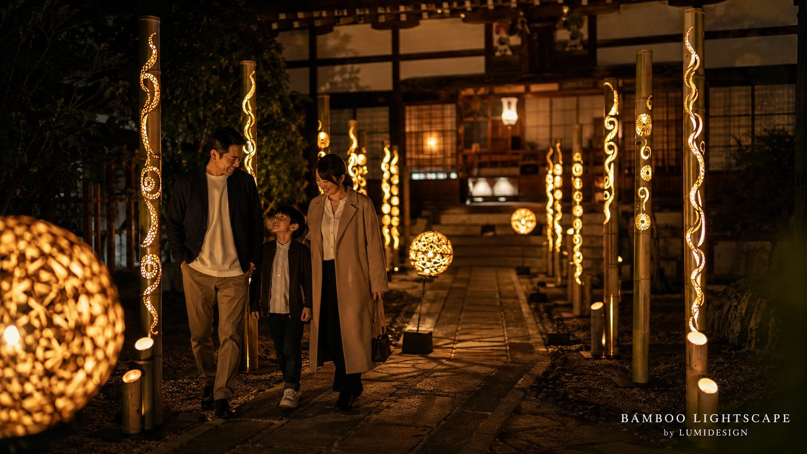BAMBOO LIGHTSCAPE by LUMIDESIGNの竹灯籠と竹鞠が灯る寺院の参道を家族が歩く夜間ライトアップの演出イメージ