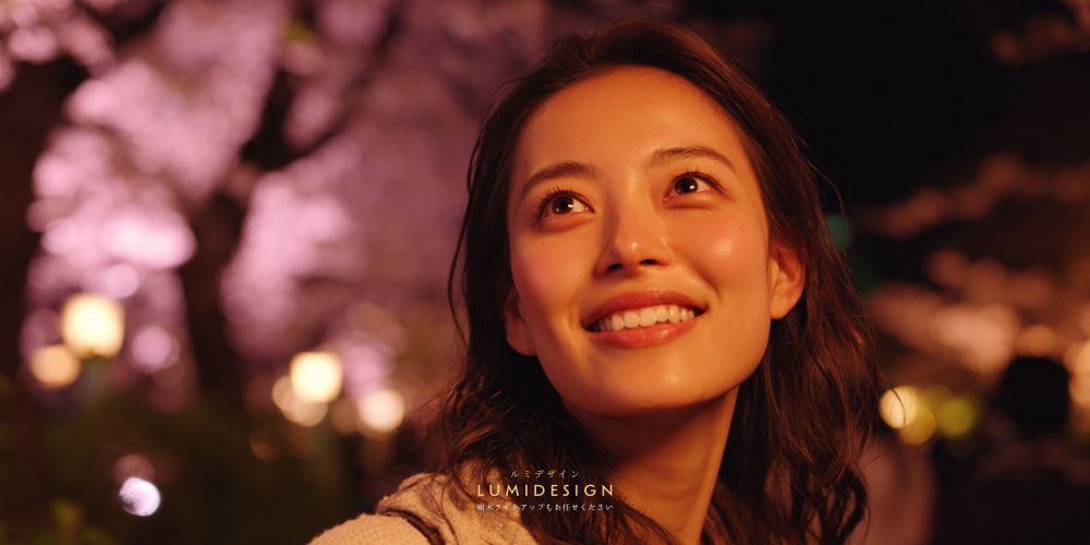 ピンク色の桜ライトアップを見て感動する女性 夜のライトアップ演出の様子